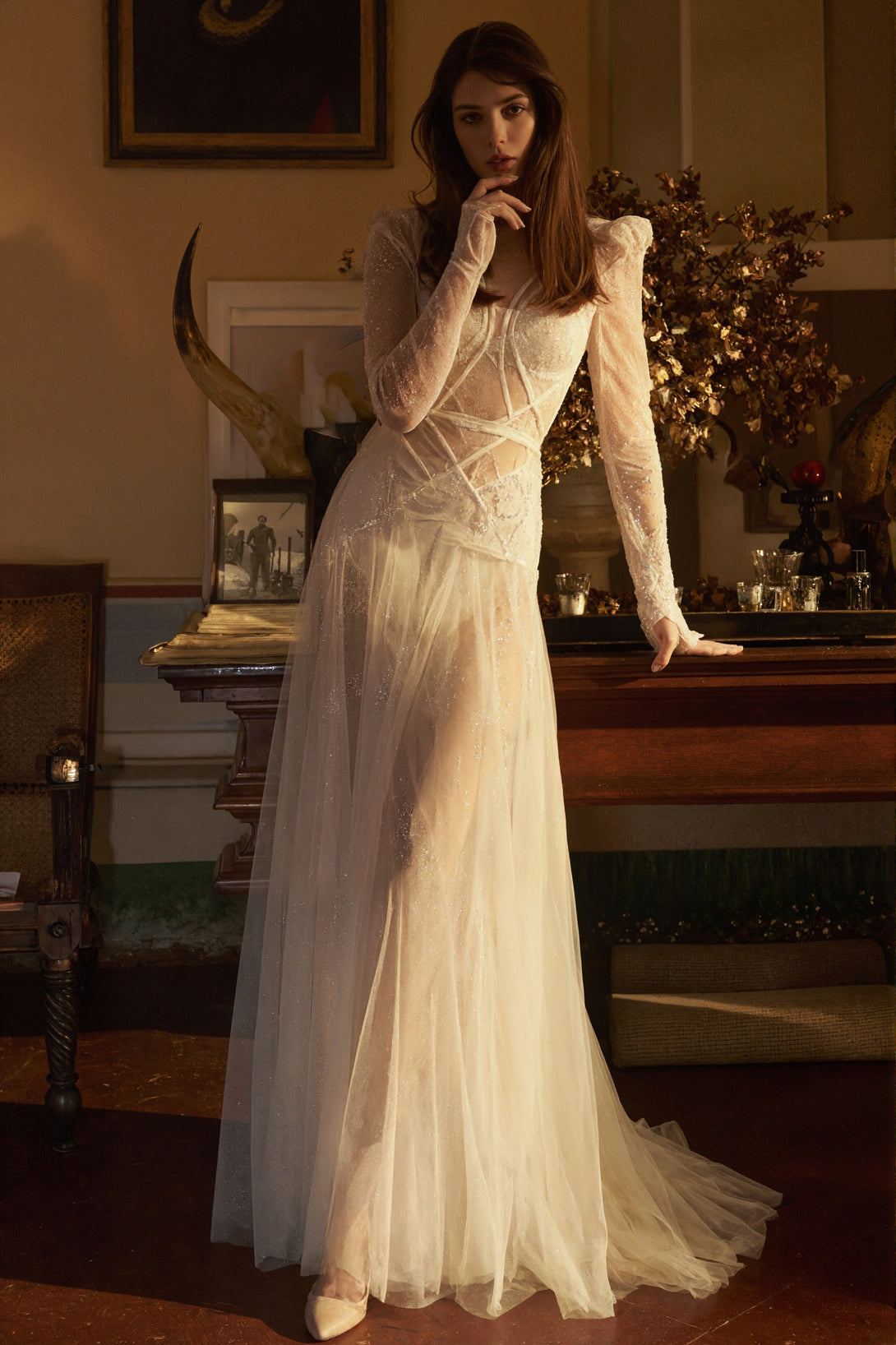 Woman in a white dress standing in a room with decorative elements.