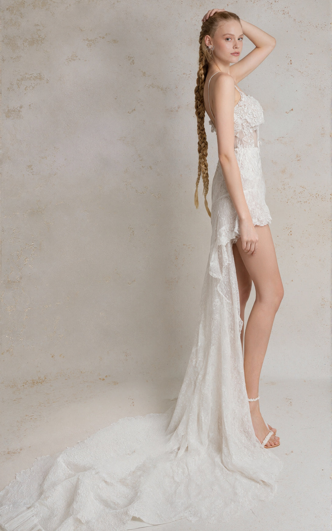 Woman in a white lace dress standing against a neutral background