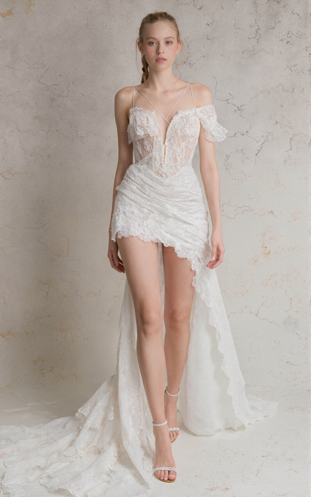 Woman wearing a white lace wedding dress against a neutral background