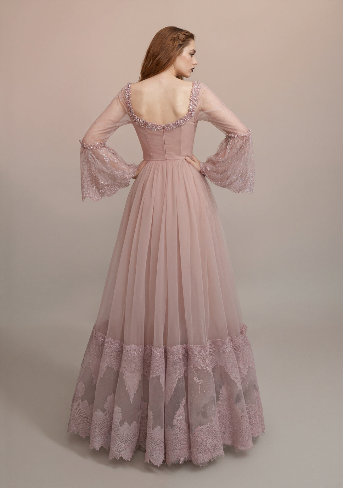 Pink lace dress with sheer sleeves on a plain background